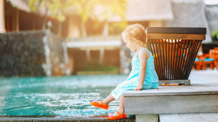 Little adorable girl splashing in outdoor pool